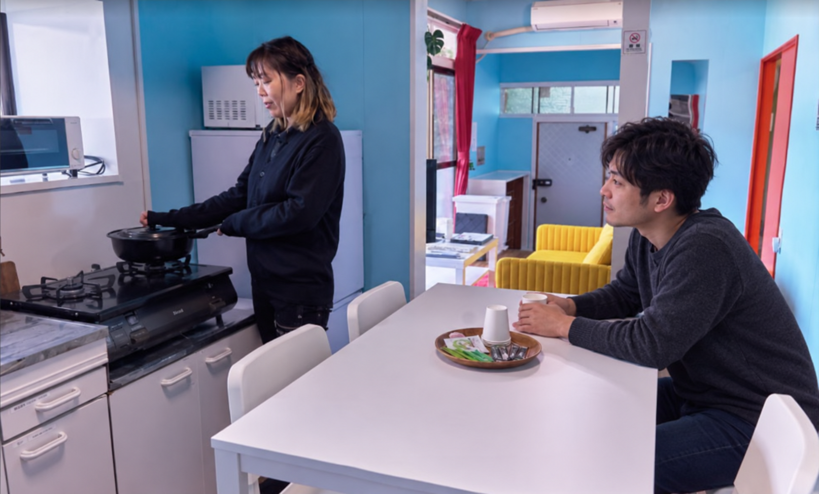 佐世保まち宿のキッチンで調理しながら食卓を囲む様子